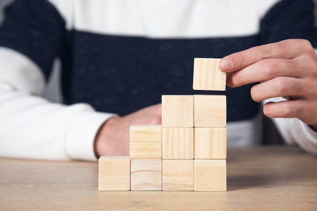 Business man holding wooden cubes on table