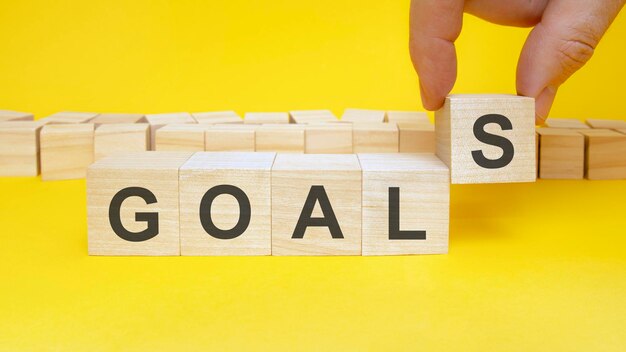 Business man holds wooden blocks with the word Goal. the concept of achieving business goals. execution of a business plan. purposefulness. perseverance. target. planning