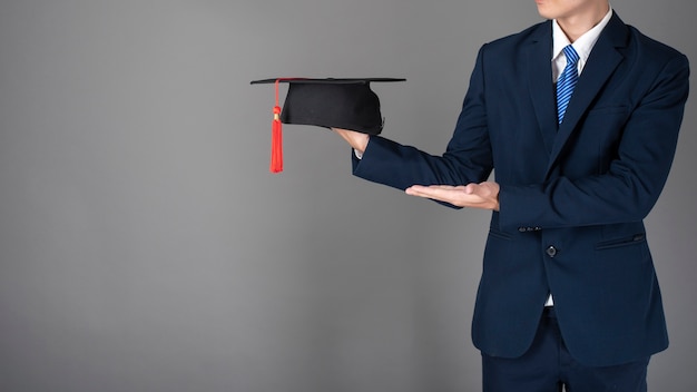 Business man is holding graduation hat, business education concept 