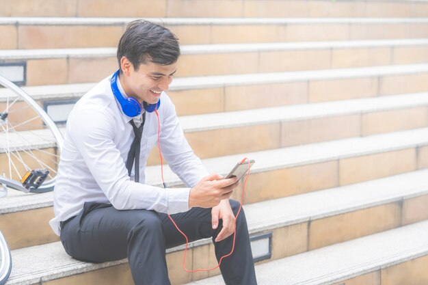 ビジネスの男性は、側に彼の自転車で音楽を聴いてリラックス