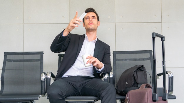 Business man is sitting on chair waiting for business trip travel with suitcase