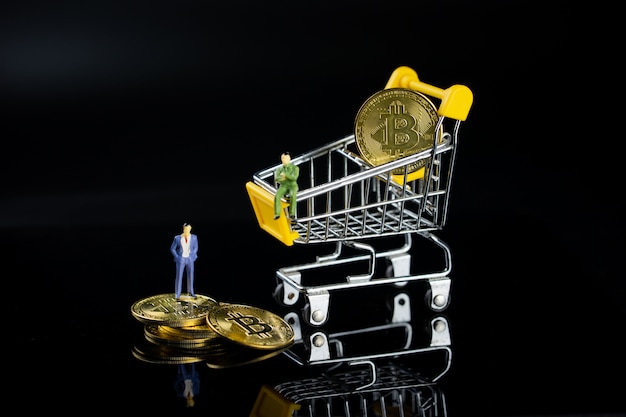 A business man is standing on the golden coins, and another is sitting on a shopping cart