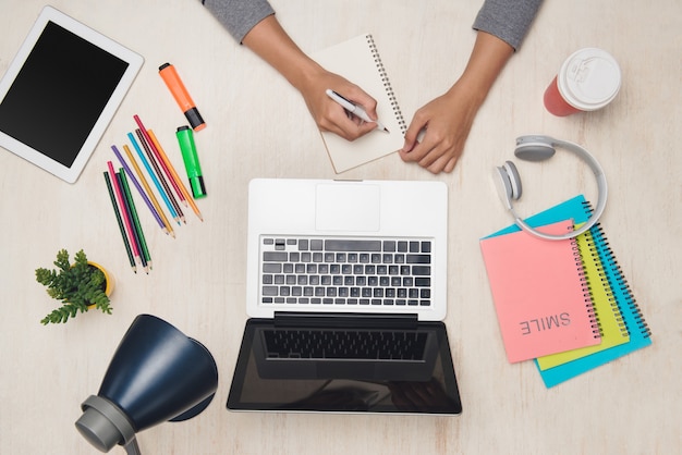 Business man is writing on blank notebook at office table. Top view, flat lay.