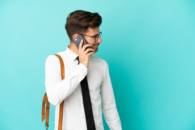 Business man over isolated background keeping a conversation with the mobile phone with someone