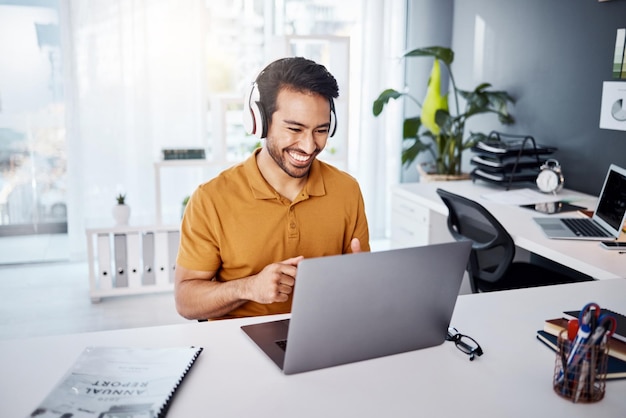 Business man laptop and headphones to listen to music audio or webinar Asian male entrepreneur at desk listening to a song or video call while online on social media with internet connection