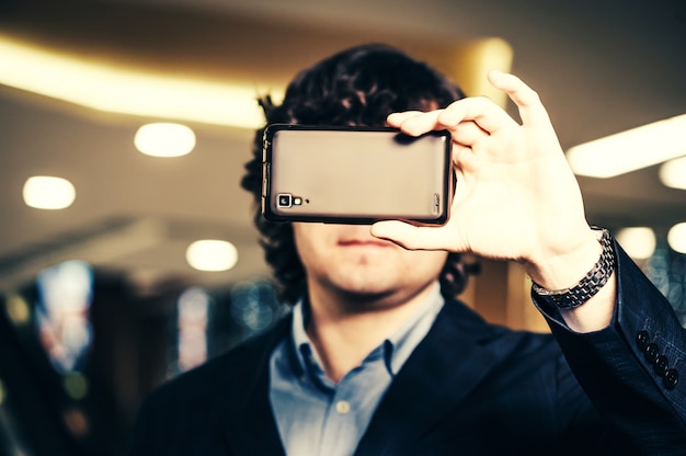 Business man looking in smartphone screen.