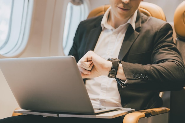 Business man looking at wrist watch during air flight travel long time late and worry about flying schedule concept