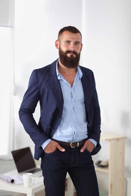 Business man or manager standing against his desk at office with  arms folded