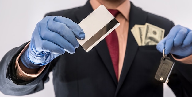 Photo business man in medical gloves holding credit card and car key, with money in poket, epidemic covi19, safety eberybody