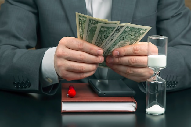 Business man in the office counts money on a of sundials