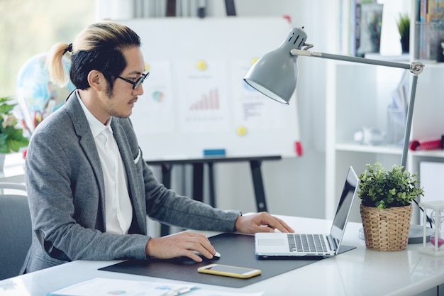 Business man in office  using laptop and cell phone,