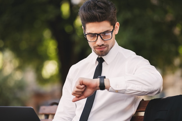 Business man outdoors in the park looking at watch clock