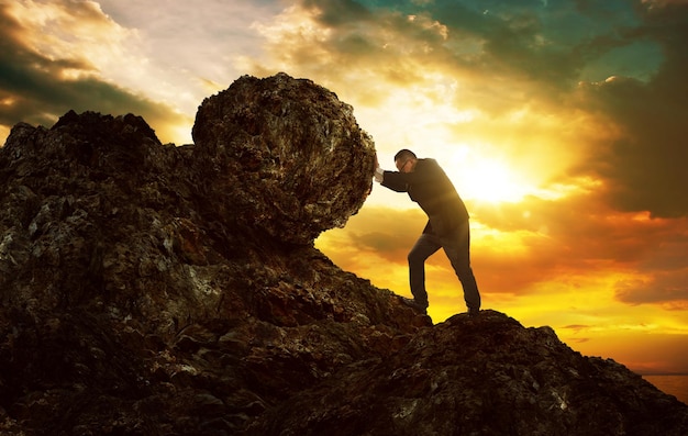 Business man pushing large stone up to hill Business heavy tasks and problems concept