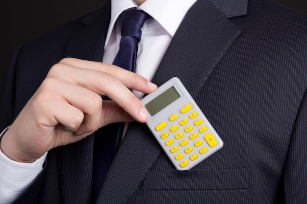 Business man putting calculator into pocket