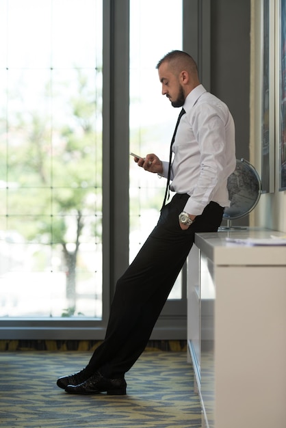 Business Man Reading Text Message On A Mobile In A Modern Office