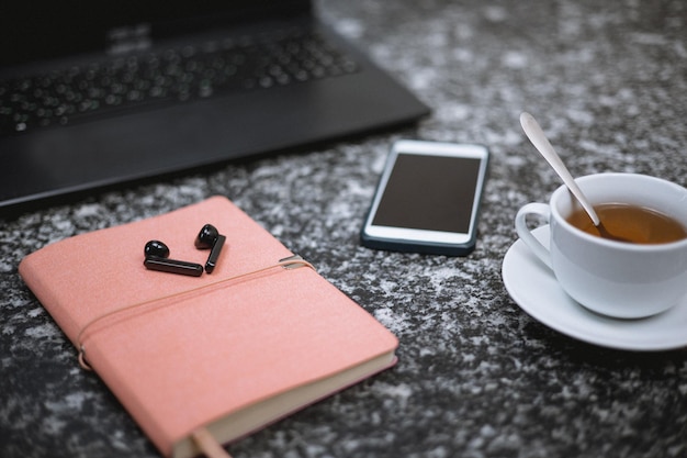 ビジネスマンのデスクトップ携帯電話とラップトップノートブック一杯のお茶とヘッドフォン