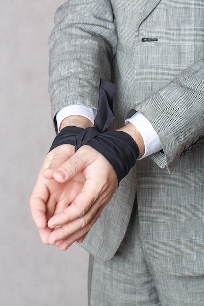 Business man's hands tied with black fabric. Closeup