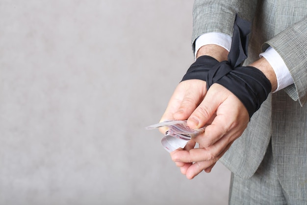 Business man's hands tied with black fabric. Closeup