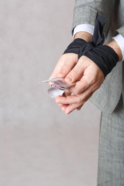 Business man's hands tied with black fabric. Closeup