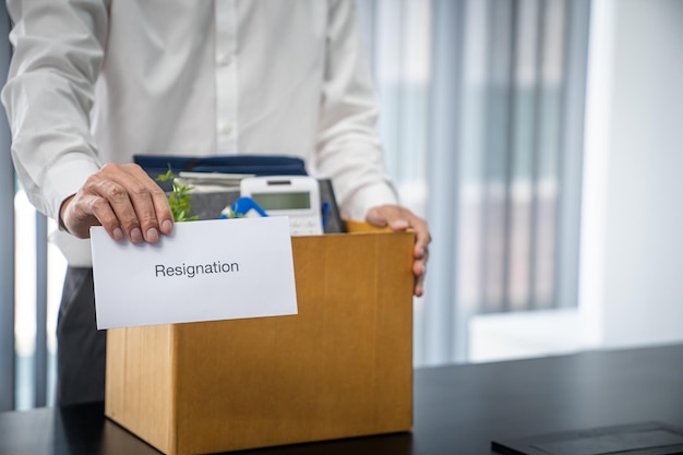 Business man sending resignation letter and packing Stuff Resign Depress or carrying business cardboard box by desk in office Change of job or fired from company