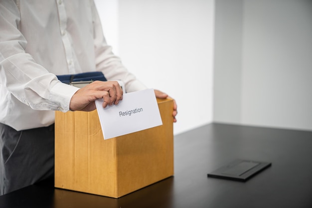 Business man sending resignation letter and packing Stuff Resign Depress or carrying business cardboard box by desk in office Change of job or fired from company