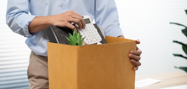 Business man sending resignation letter and packing Stuff Resign Depress or carrying business cardboard box by desk in office Change of job or fired from companyxA