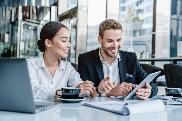 Business man sharing his ideas with tablet to asian female colleague