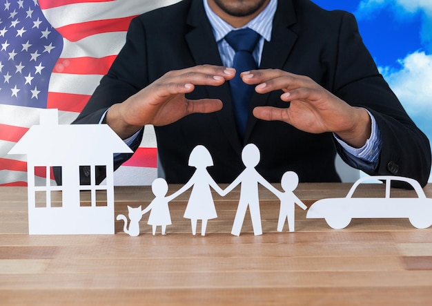 Business man showing family, car and house on paper against american flag