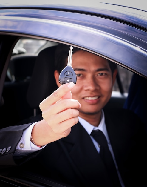 Business man showing key and sit in car