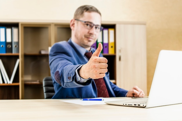 Business man shows thumb up sign gesture Desktop in the office Successful office worker