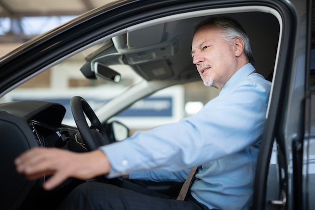 Business man sitting on a car at a car dealer saloon