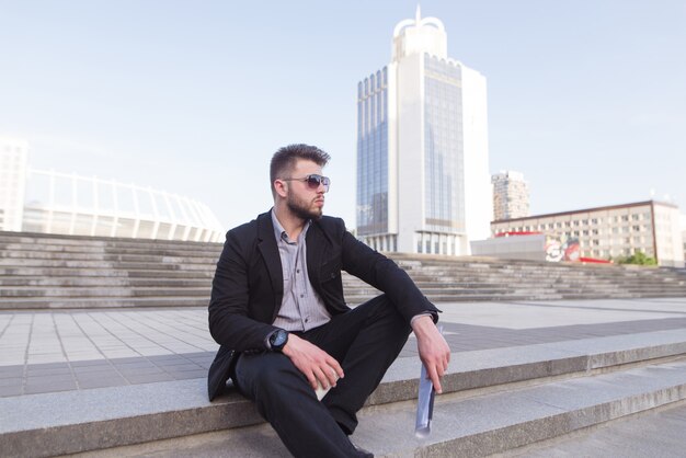 Business man sitting on stairs against the backdrop of modern architecture.