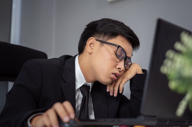 деловой человек сонный на рабочем столе между использованием портативного компьютера