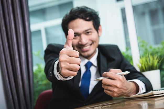 Business man smiling showing thumbs up, focus hand