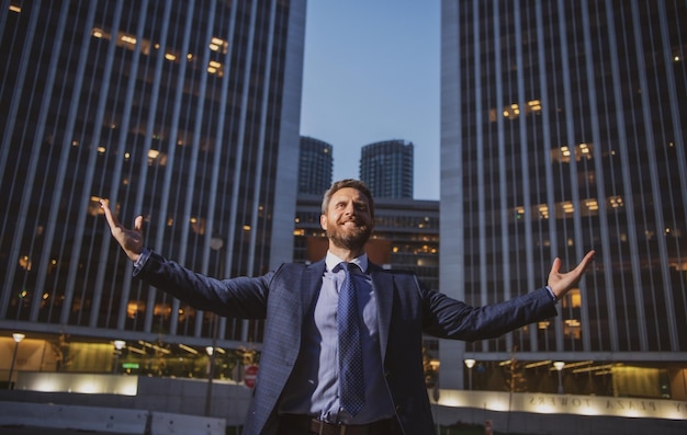Фото Деловой человек встает и ночной город на фоне бизнесмена, поднимающего руки возле городского офиса