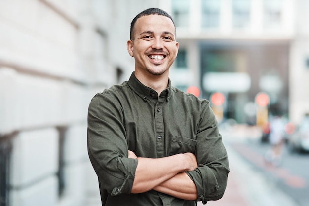 Business man standing with arms crossed looking confident and proud in the city alone Portrait of a black male entrepreneur or worker showing vision ambition and success with arms folded downtown