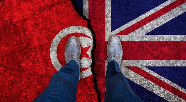 Photo business man stands on cracked flag of uk and tunisia political concept