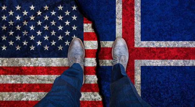 Business man stands on cracked flags of USA and Iceland Political concept