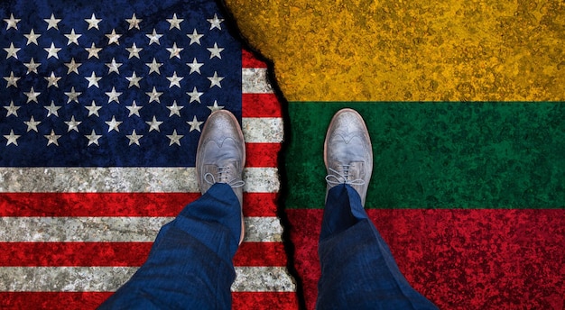 Business man stands on cracked flags of USA and Lithuania Political concept