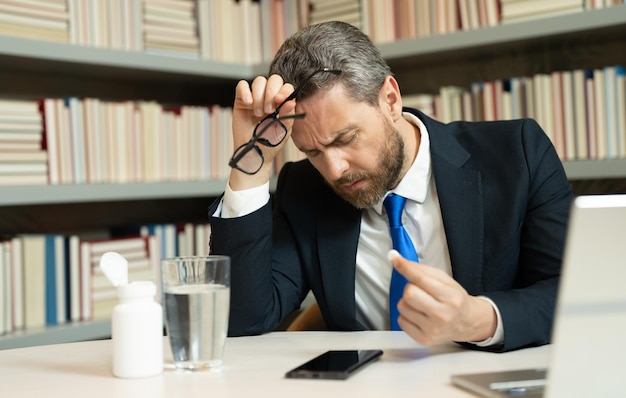 business man suffering from headache after computer work exhausted with closed eyes touching head re