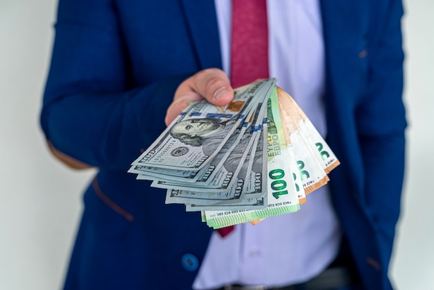 為替レートのユーロとドル紙幣を保持しているスーツのビジネスマン。財務コンセプト。