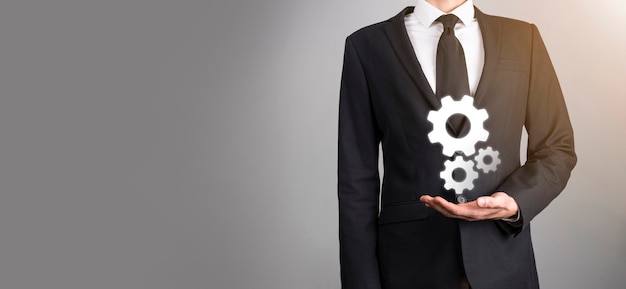 Business man in suit holding metal gears and cogwheels mechanism representing interaction teamwork concept,hand hold group of virtual cog gears wheel