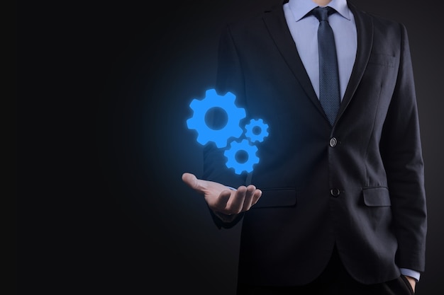 Business man in suit holding metal gears and cogwheels mechanism representing interaction teamwork concept,hand hold group of virtual cog gears wheel.