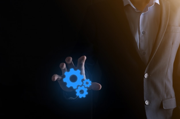 Business man in suit holding metal gears and cogwheels mechanism representing interaction teamwork