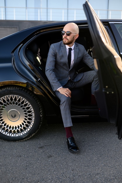 Business man in suit opening black car door