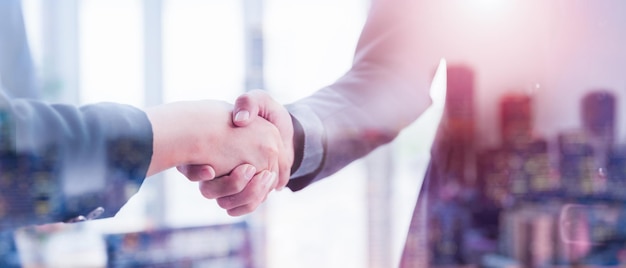 Foto uomo d'affari in giacca e cravatta stringe la mano per concordare un accordo di partnership commerciale concetto di etichetta aziendale di congratulazioni concetto di stretta di mano durante la riunione d'ufficio doppia esposizione di affari