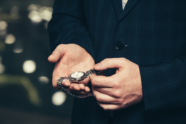 Business man in a suit shows his wristwatch.