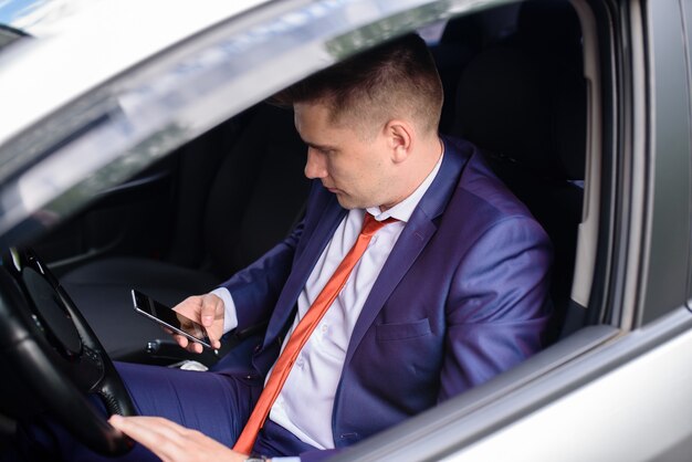 Business man talking on mobile phone in car.