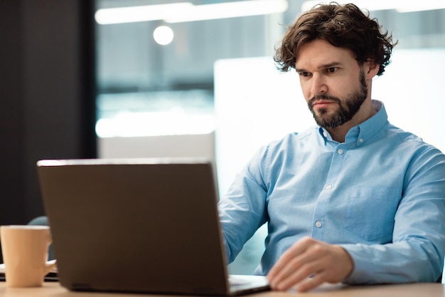 Foto uomo d'affari con laptop seduto alla scrivania in ufficio