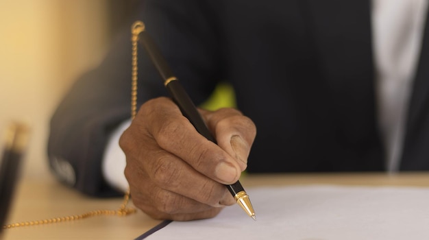 Business man using a pen to sign a agreement document paper to
approve by signature hand of business man working on contract
paperwork in office concept of deal on business desk